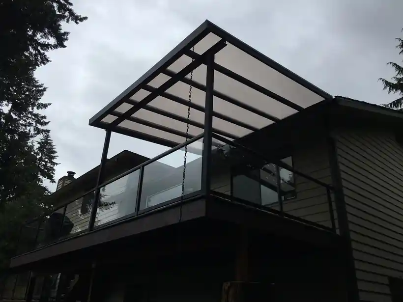 Dark polycarbonate cover over a glass-railed balcony at dusk
