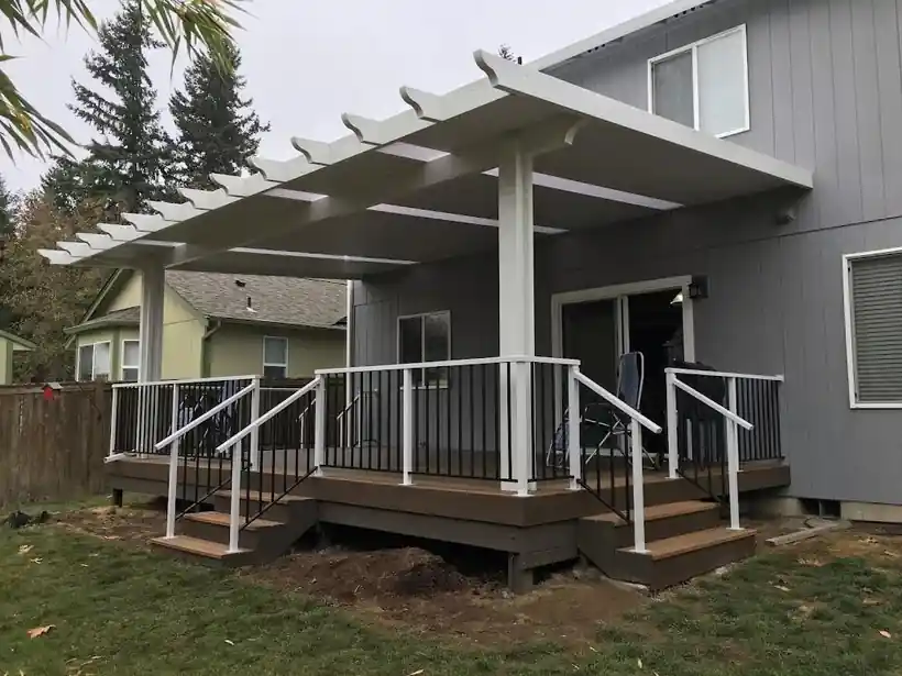 White aluminum pergola-style cover over a deck with white rails and black balusters