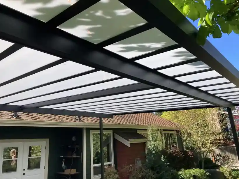 Black frame glass cover over a patio with glass doors
