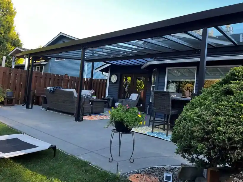 Glass patio cover over a furnished patio with water in the background